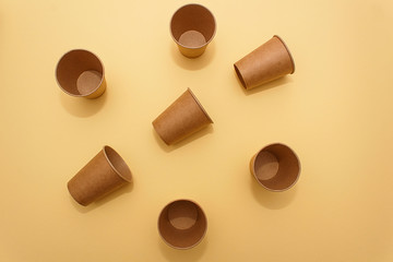 Many craft paper cups for coffee or any drinks on a  yellow paper background. Concept of ziro waste, no plastic