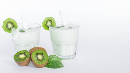 milk and fruit cocktail in glass glasses and halves of fresh kiwi close-up. background with milk and fruit cocktail and slices of kiwi.