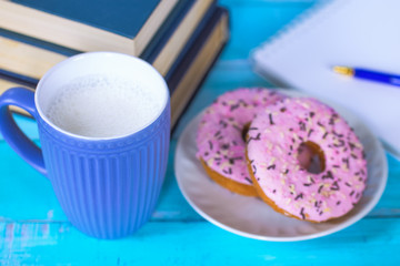 background with books, a Cup of milk and doughnuts close-up.