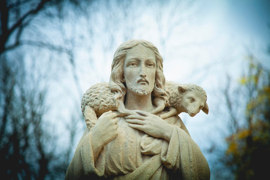 Ancient stone statue of Jesus Christ Good Shepherd with the lost sheep on his shoulders. Biblical history, religion, Christianity, God concept.