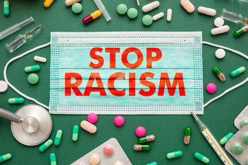 Stop racism text on a medical mask, green health background.
