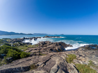 Waves on the stones of Praia da Arma&ccedil;&atilde;o on a sunny day.