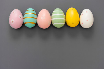Easter eggs in row, decorative abstract colorful eggs. Over grey background, top view.