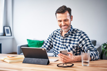 Man checking his smartphone while working from home