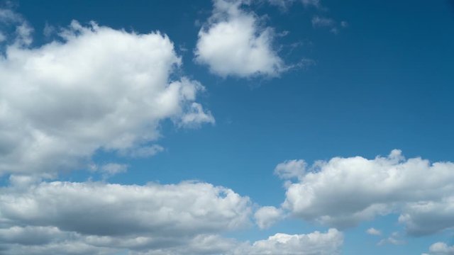 Time lapse of white fluffy cumulus clouds that flow from left to right in the blue sky