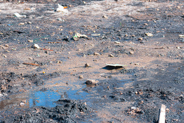 Polluted area. Wet land with puddles and trash. Ecological problem. Rain washed out road.