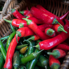 Green and red chilli hot peppers in a wicker basket at farmers market