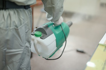 Disinfecting of office to prevent COVID-19, person in white hazmat suit with disinfect in office, coronavirus concept