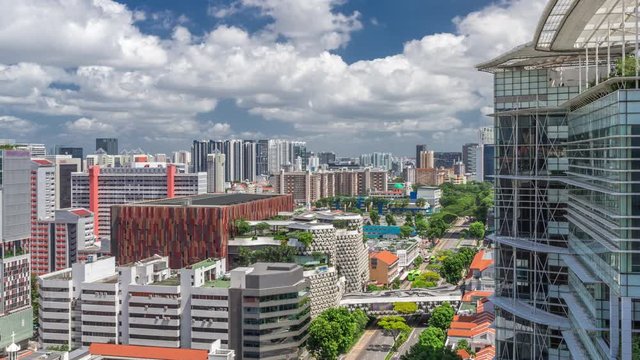 Singapore skyline with Victoria street and National Library aerial timelapse hyperlapse. Green trees on the road with traffic. Clouds on a blue sky