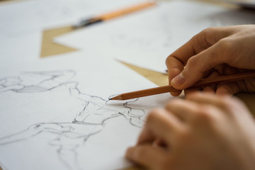 A top view flat lay of many figure drawing pencil and marker sketches. The artist worskspace with male and female drawings and pencils on the white paper, art, craft, creativity, inspiration, concepts