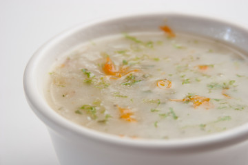 Closeup of a chicken soup served on a white bowl