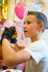 Fototapeta na wymiar The handsome little boy eating burger in black rubber gloves.