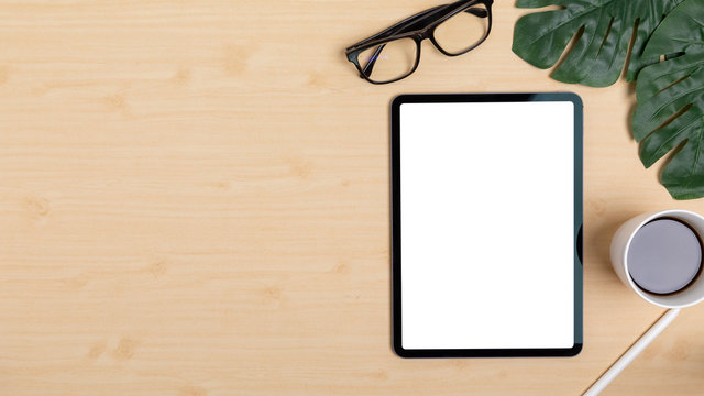 Wooden Table Office desk top view design workspace layout right have plant, coffee cup, pen, glasses near show mock up tablet isolated and empty left area for insert text or other - Powered by Adobe