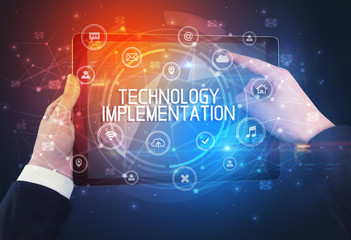 Close-up of a tablet with TECHNOLOGY IMPLEMENTATION inscription, innovative technology concept