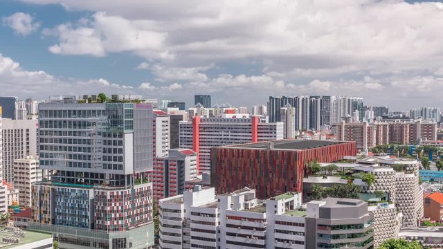 Singapore skyline with Victoria street and shoping mall aerial timelapse. Green trees on the road with traffic. Clouds on a blue sky