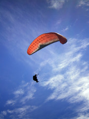 Épine mountain, France - August 5th 2008 : Focus on a blue and orange paraglider in mid flight. We can see a beautiful blue sky in the background.