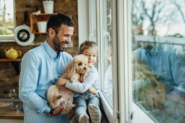 Happy father and daughter enjoying with their dog at home.