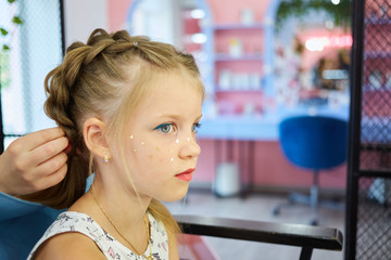 Hairdressing services. Reating hairstyle. Hair styling process. Children hairdressing salon