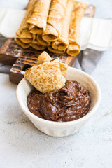 Crepes - sweet thin golden fried pancakes. Vegan, vegetarian dessert. Crepes rolled up into tubes  and chocolate sweet hazelnut dessert cream paste