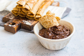 Crepes - sweet thin golden fried pancakes. Vegan, vegetarian dessert. Crepes rolled up into tubes  and chocolate sweet hazelnut dessert cream paste