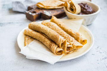 Crepes - sweet thin golden fried pancakes. Vegan, vegetarian dessert. Crepes rolled up into tubes on parchment paper