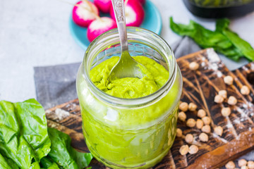 Green spinach chickpea hummus in glass jar. Vegan, vegetarian healthy food.