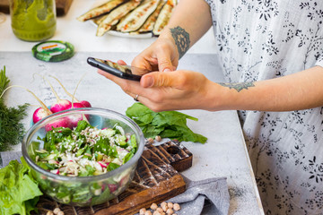 Phone picture of food. Hands make smartphone photography of summer fresh kale, cabbage salad for social media blogging. Concept for online order services. Vegan meal.
