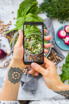 Phone picture of food. Hands make smartphone photography of summer fresh kale, cabbage salad for social media blogging. Concept for online order services. Vegan meal.