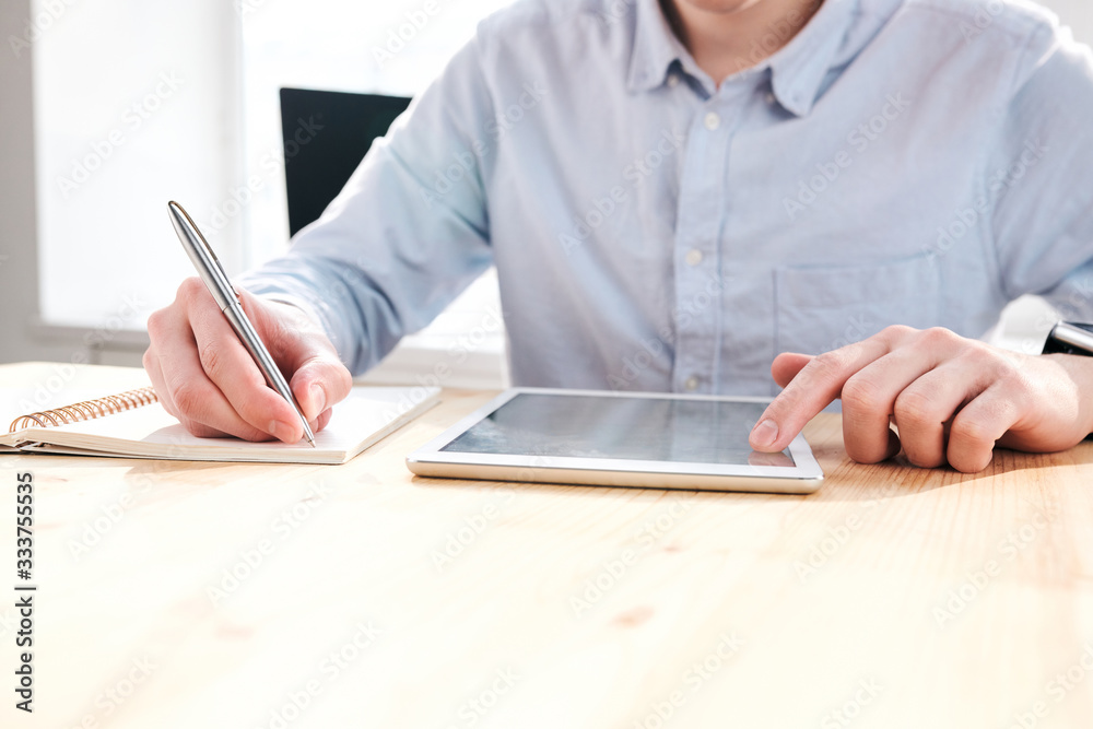 Aufkleber Close-up of unrecognizable marketer sitting at desk and using tablet while working with social medias