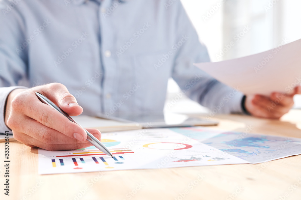 Poster close-up of unrecognizable businessman sitting at table and discussing business charts at meeting