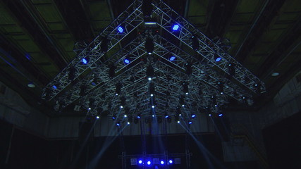 Disco Concert Blinking flashing Lights on truss structure spotlights in stage construction framework light show performance. Dancing crowd peoples silhouettes.