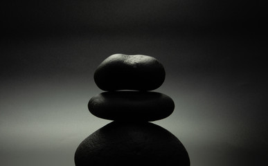 black stones in the shape of a pyramid, black background with backlight