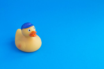 Yellow toy duckling for bathing on the blue  background. Copy space. Closeup.
