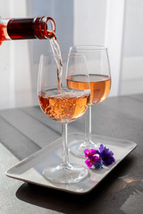 Pouring of rose wine from Provence in two glasses in sunny day