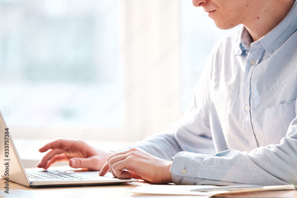 Aufkleber Close-up of busy man sitting at table and using laptop while analyzing internet resources