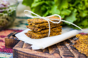 Crispy low calories flax seeds flatbread.  Dehydrated vegan healthy bread on parchment paper with thread.