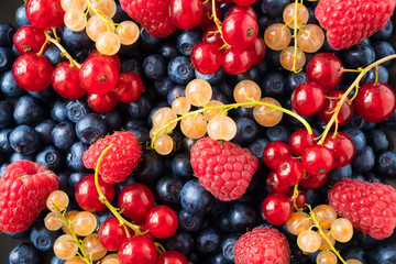 Background of fresh berries and fruits. Ripe bilberries, blueberries, currants, and raspberries. Mixed berries and fruits. Top view. Background berries and fruits. Various fresh summer fruits.