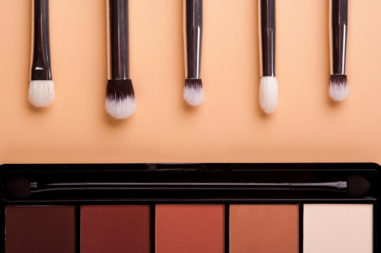 Cosmetic palette with brushes lies on a beige background