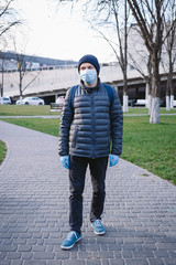 Young man in surgical mask and gloves walk on the street. Pandemic coronavirus 2020. Quarantine. 