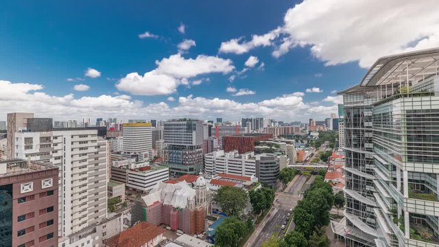 Singapore skyline with Victoria street and National Library aerial timelapse. Green trees on the road with traffic. Clouds on a blue sky