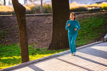 An elderly woman goes in for sports at sunset.