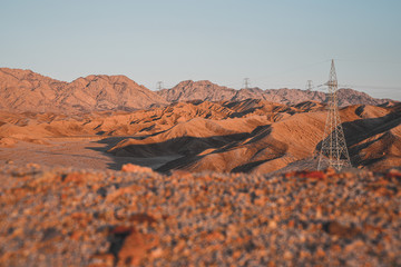 High voltage power lines of Aqaba in the sunset light on the sandstone supply electricity to the...