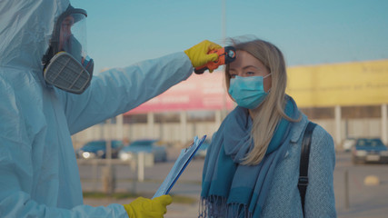 Controlling people's temperature at the entrance to airport railway station check woman the...
