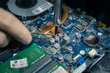 A close-up of an electrician repairing a computer circuit board,close up electrician hands are...