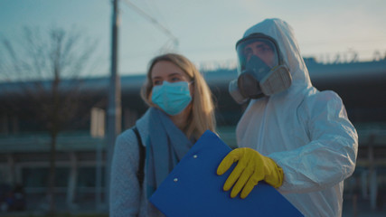 Medical worker in a protective suit screening passenger to check the Covid-19 symptoms coronavirus...