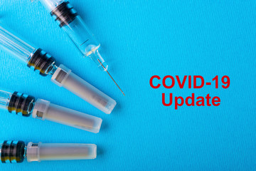 COVID-19 UPDATE text with medical syringe on blue background. Covid-19 or Coronavirus Concept