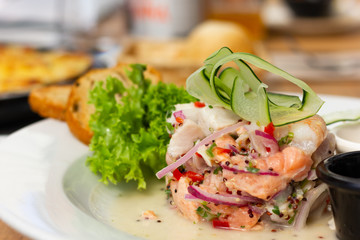 Traditional fish and shrimp ceviche with onion with zucchini on top. Delicious raw plate from Peru decorated with green vegetables. Healthy eating, gourmet restaurant concepts