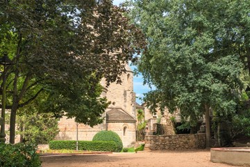 Girona, Spain, August 2018. A fragment of a medieval monastery through the foliage of an old park.