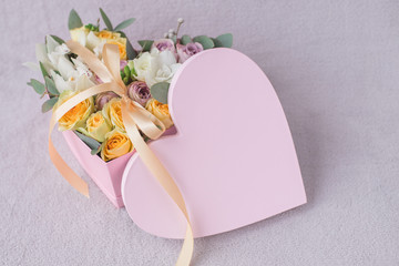 Stylish flowers arrangement in a pink hatbox. White orchid, purple and yellow roses with bunch. Birthday present. Flowers bouquet on background whith copy spase. Romantic concept