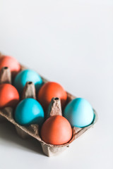 Painted easter eggs in carton box on white background. Trendy blue and red color. Top view. Paschal concept.
